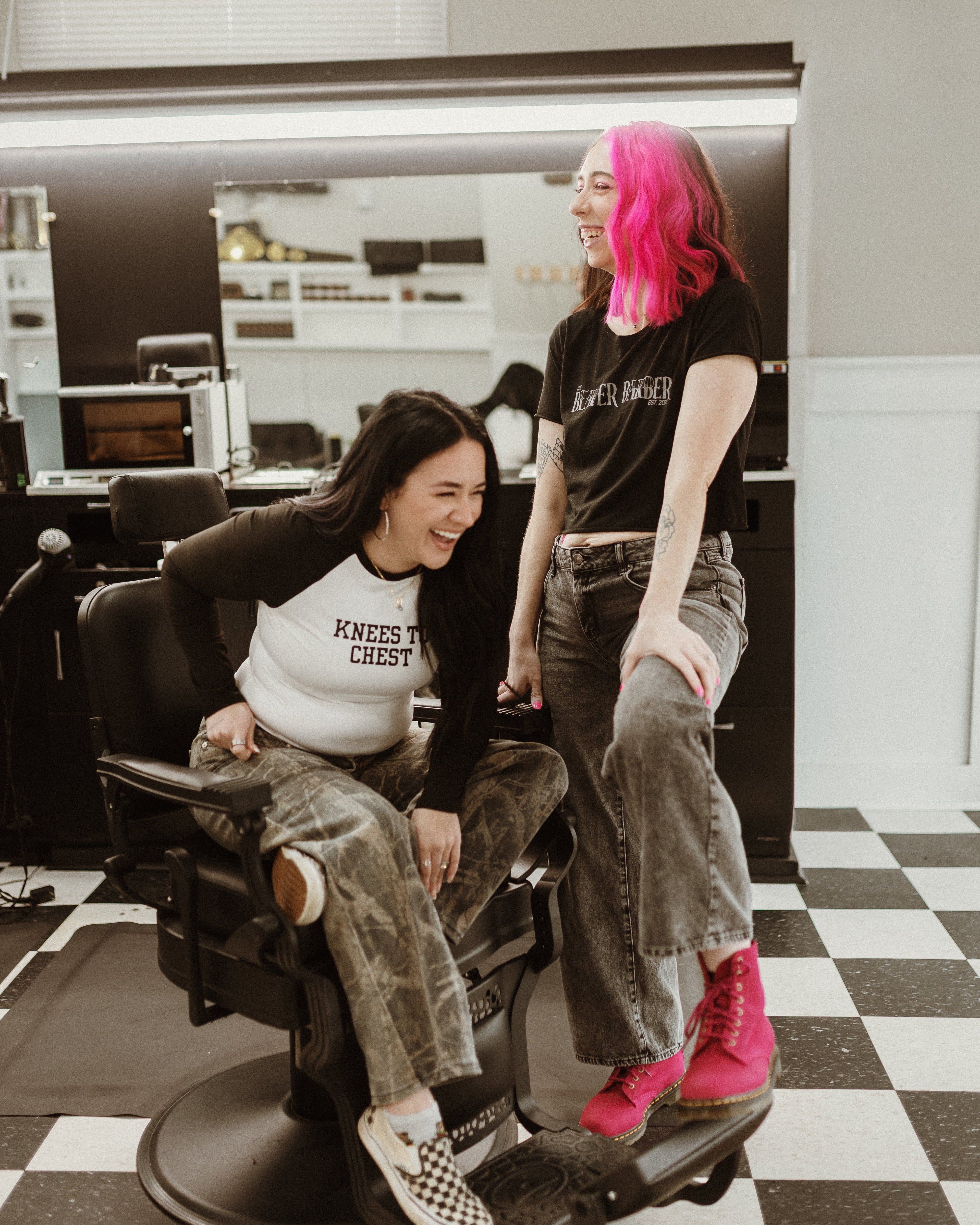 Two women in a salon setting with one sitting in a chair and the other standing.