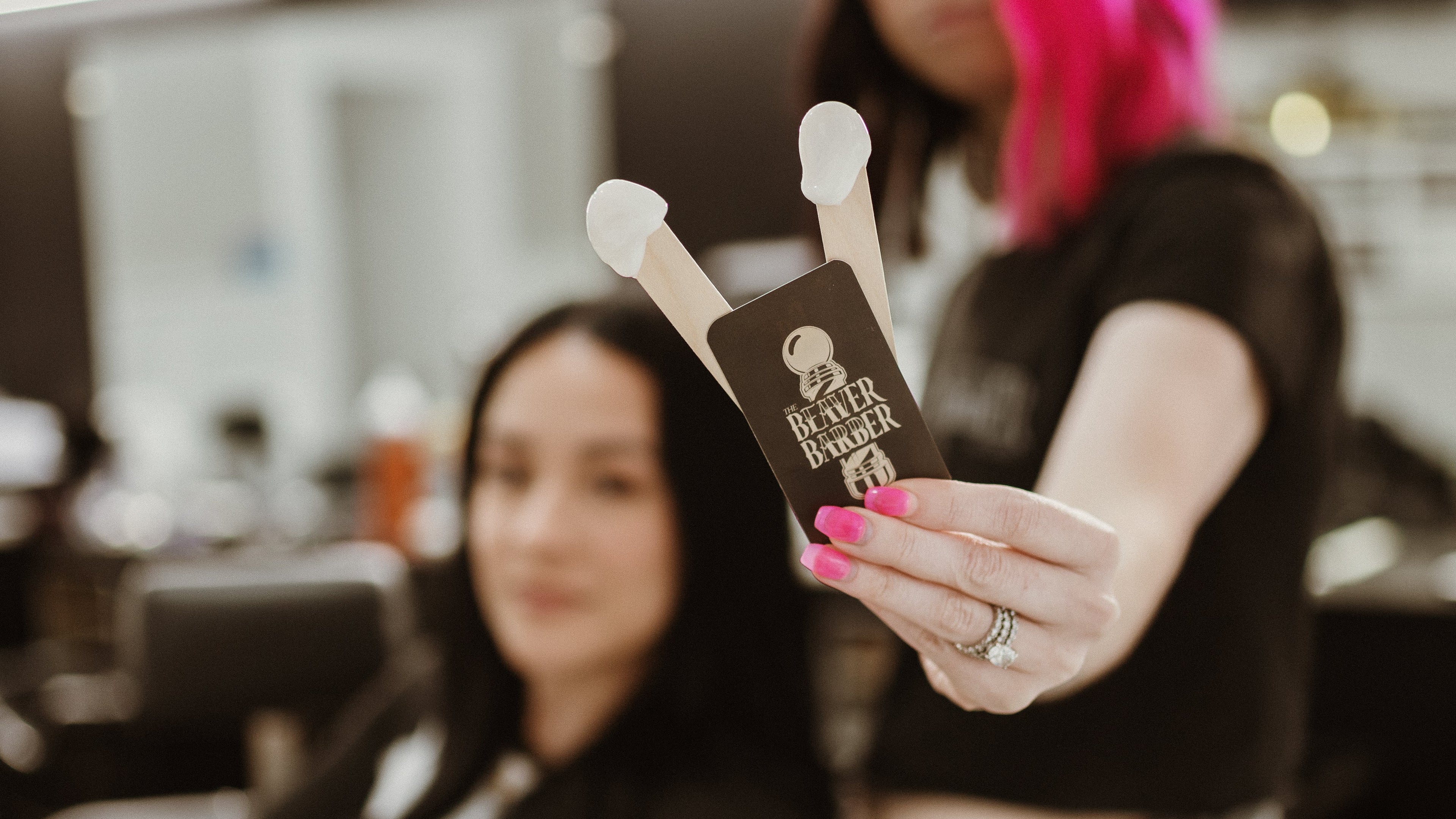 Woman with pink hair holding a product in a salon setting