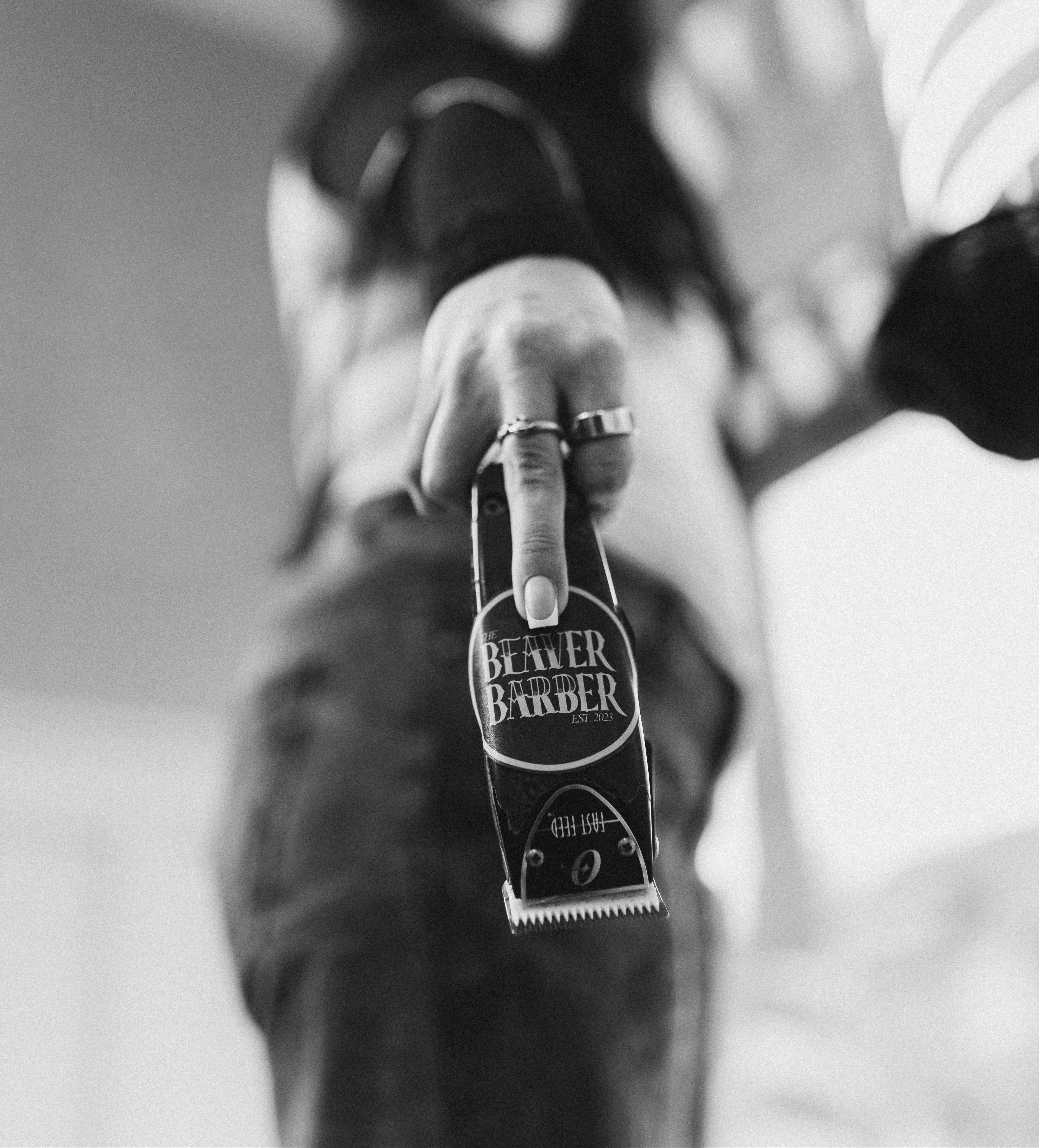 Person holding a bottle labeled 'Beaver Barber' with a blurred background